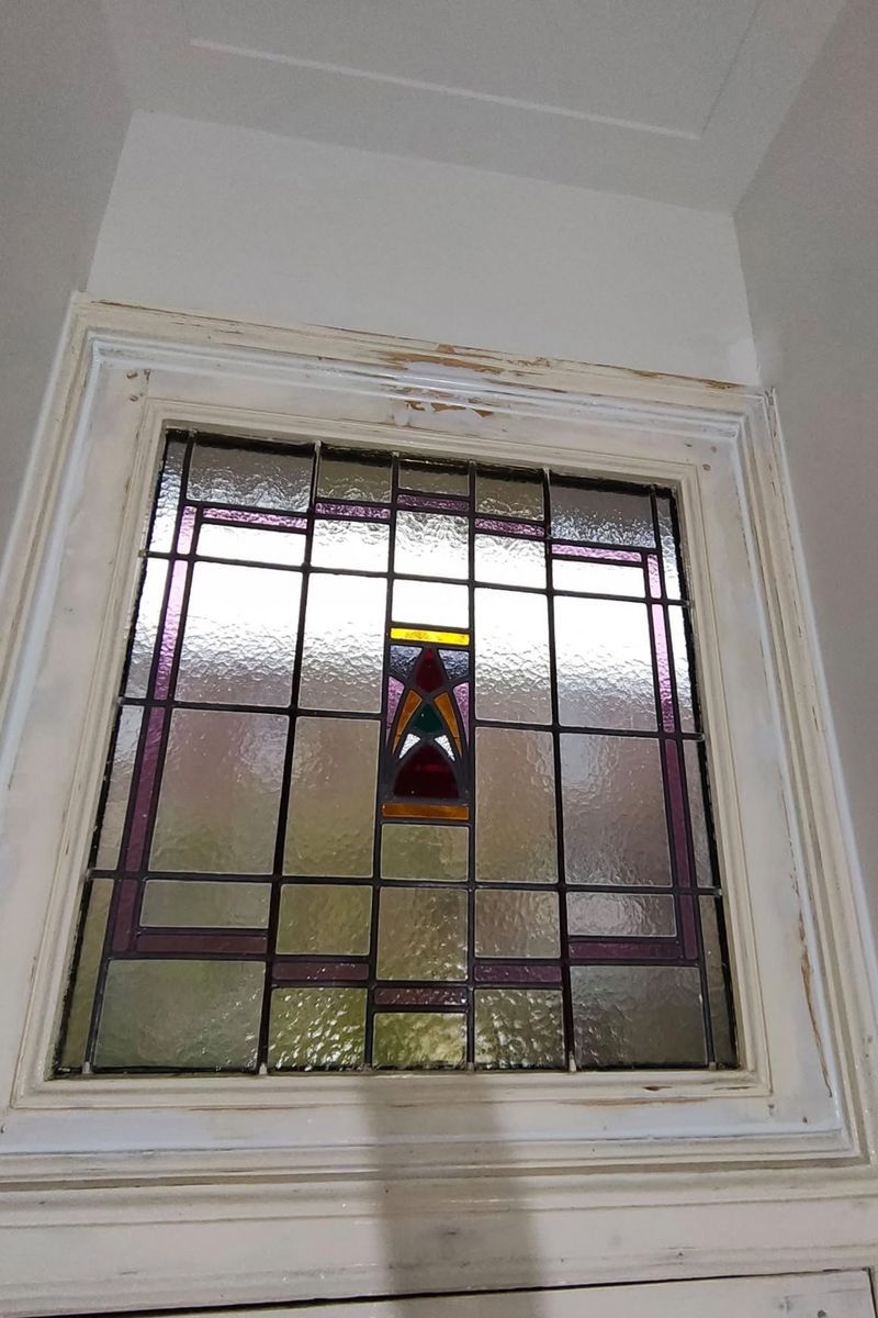 Voor: kozijn rond glas-in-lood met afgebladderde verf