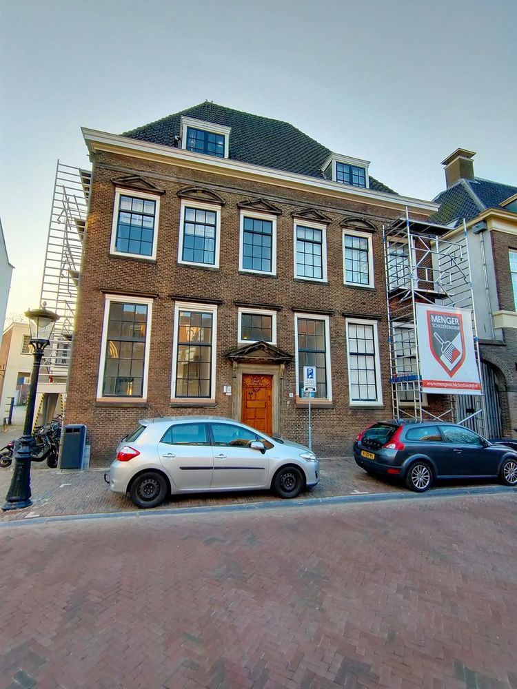 Monumentaal pand met steigers en spandoek van Menger