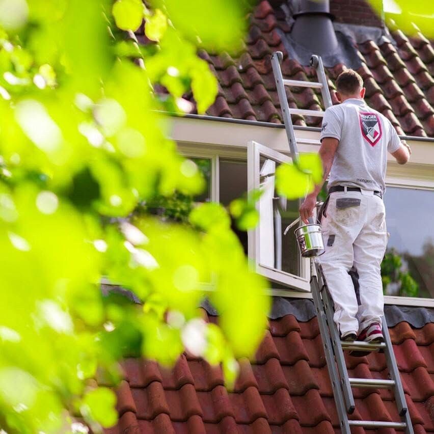 Schilder van Menger op een ladder, aan het werk aan een dakkapel